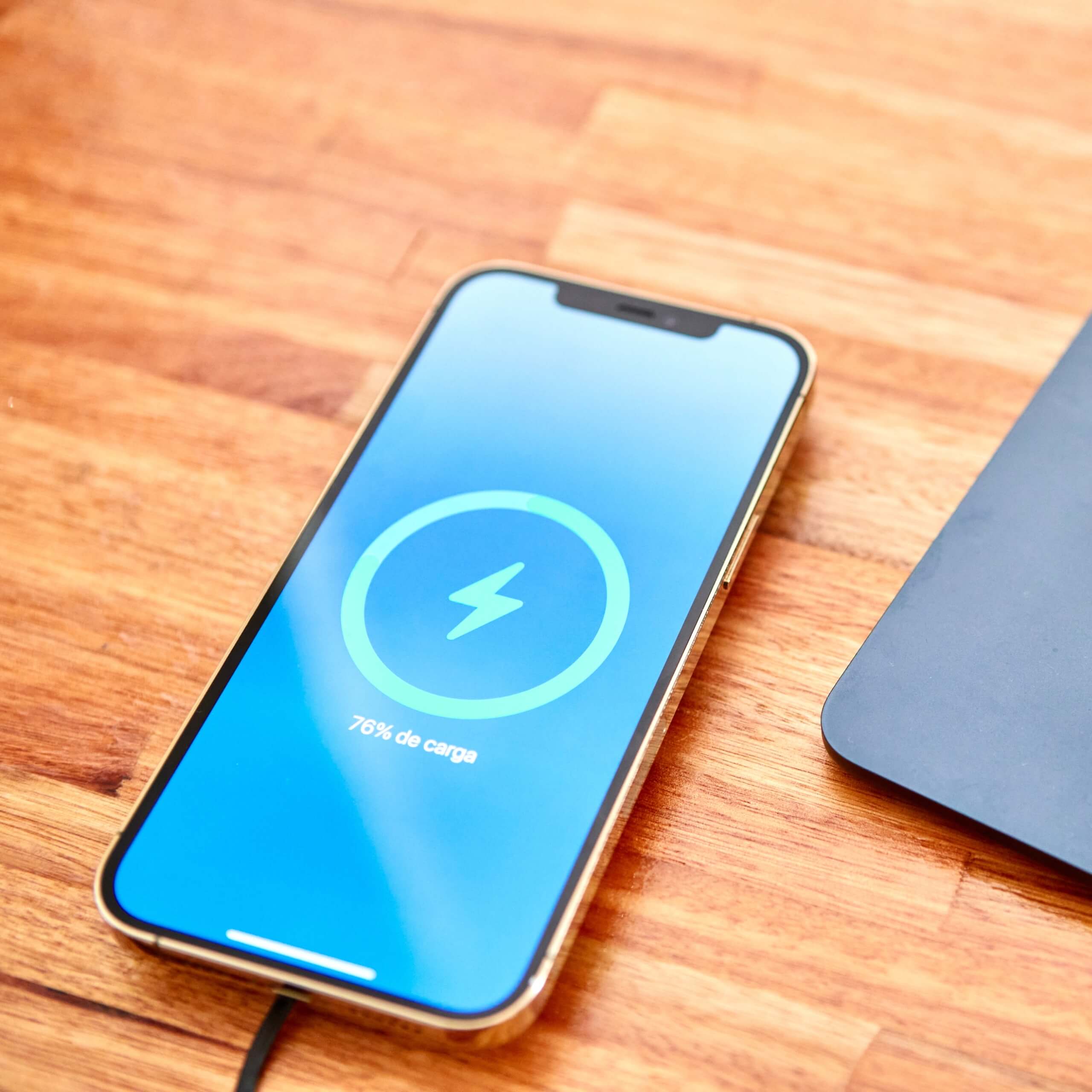 iPhone cargando al 76% con base inalámbrica sobre escritorio de madera – carga rápida con tecnología IEY.