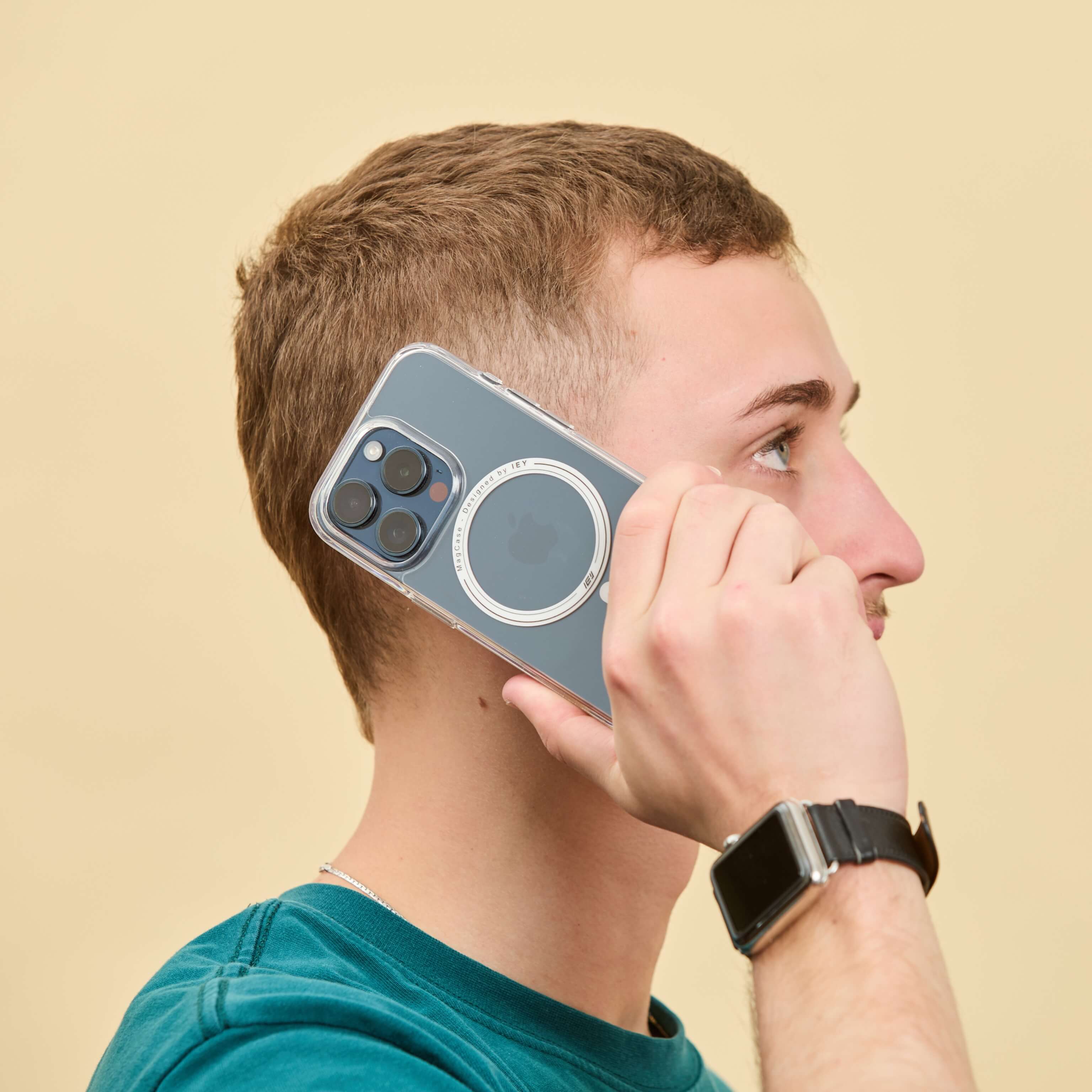 Hombre usando iPhone con funda MagSafe transparente en una llamada, vista lateral que destaca el diseño premium y aro imantado visible