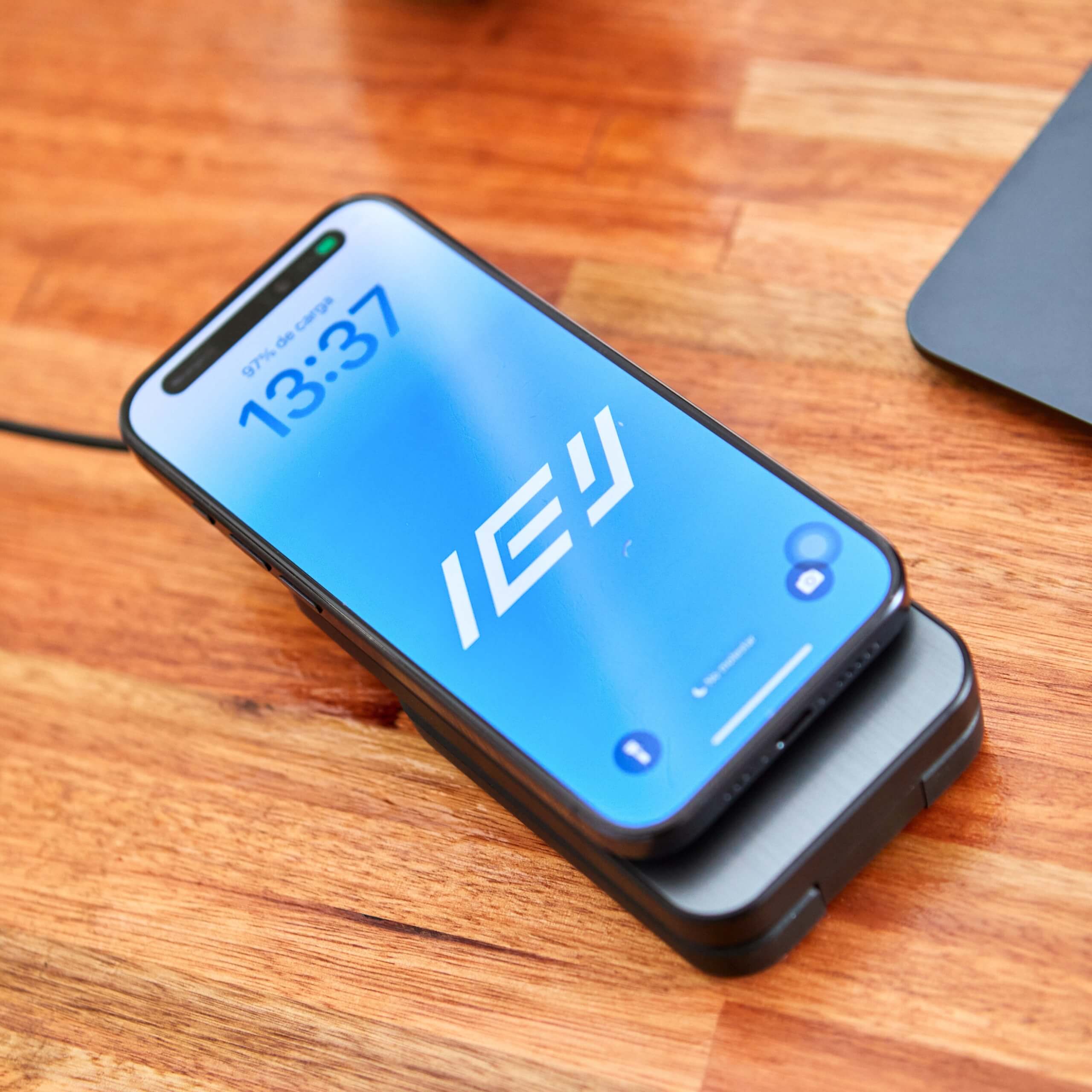 iPhone cargando con base inalámbrica negra sobre escritorio de madera