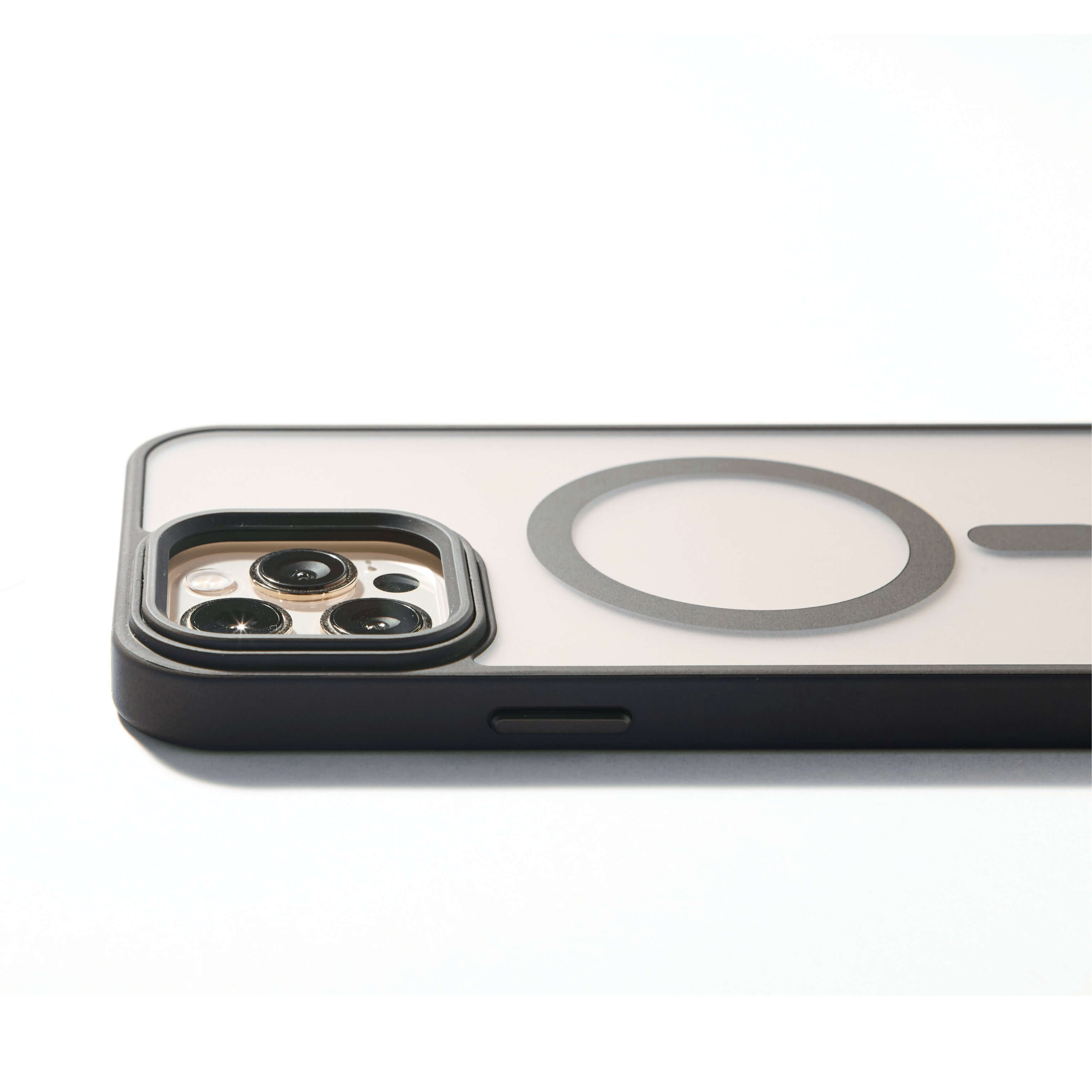 Funda MagSafe negra para iPhone apoyada de lado, con aro imantado visible y bordes elevados de protección para cámara