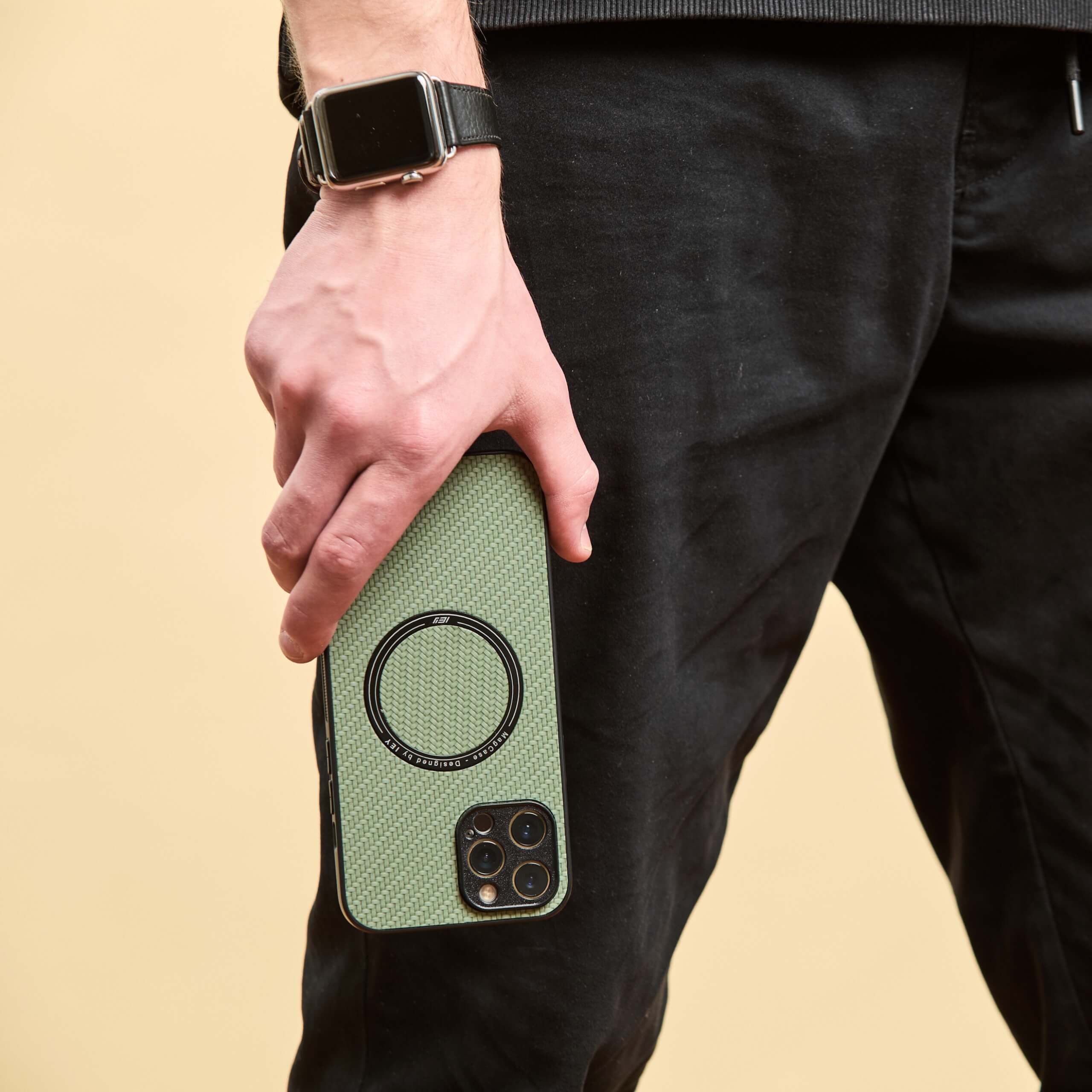 iPhone con funda MagSafe verde sostenido en posición vertical hacia abajo.