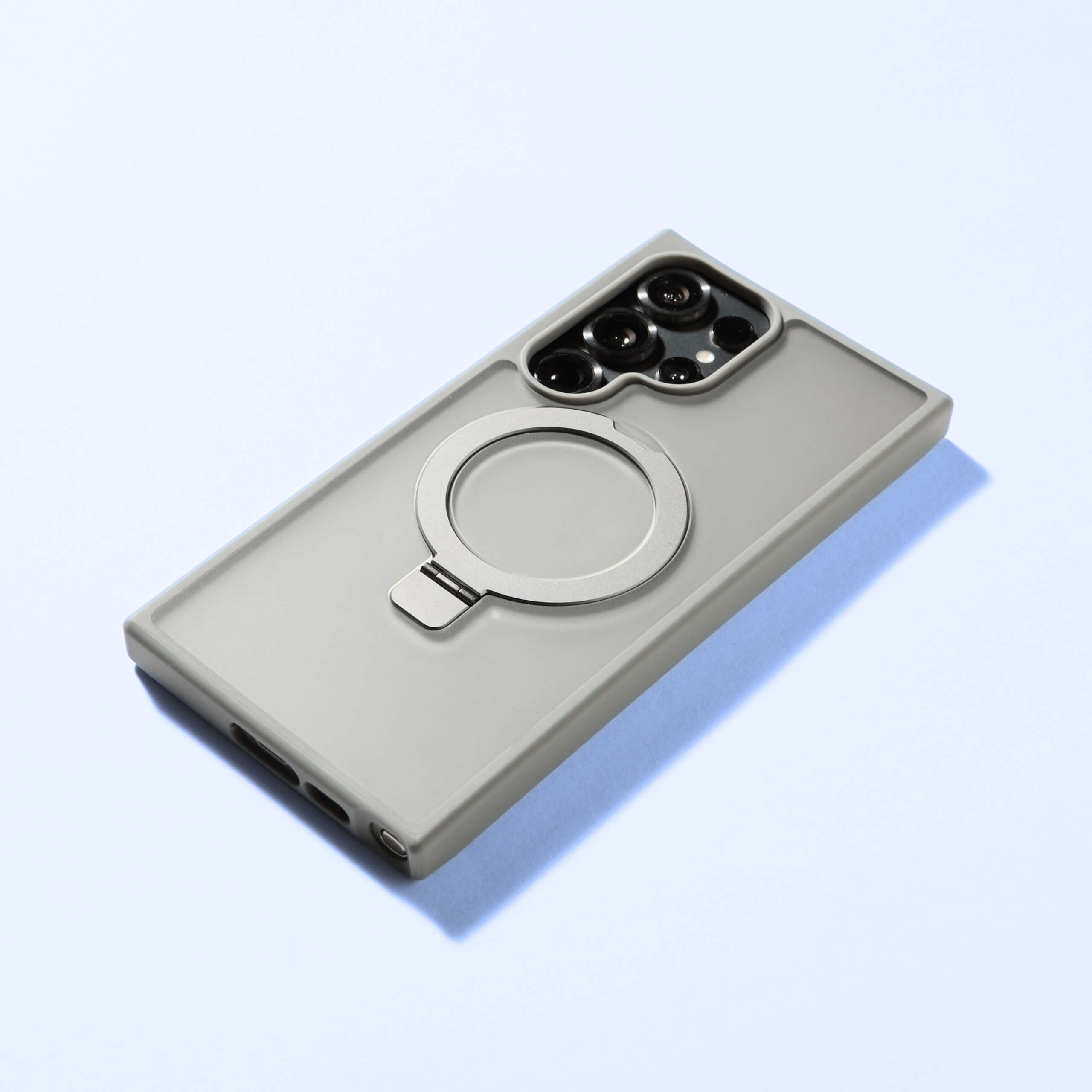 Funda MagSafe Ring gris para Samsung S25 Series vista trasera en superficie azul clara.