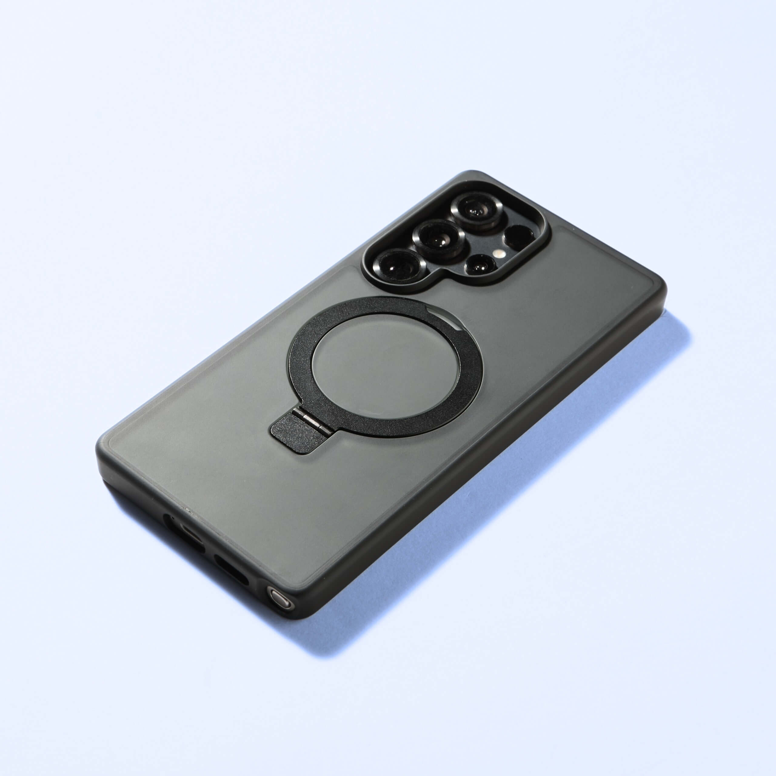 Funda MagSafe Ring negra para Samsung S25 Series vista trasera sobre fondo azul claro. #color_negro