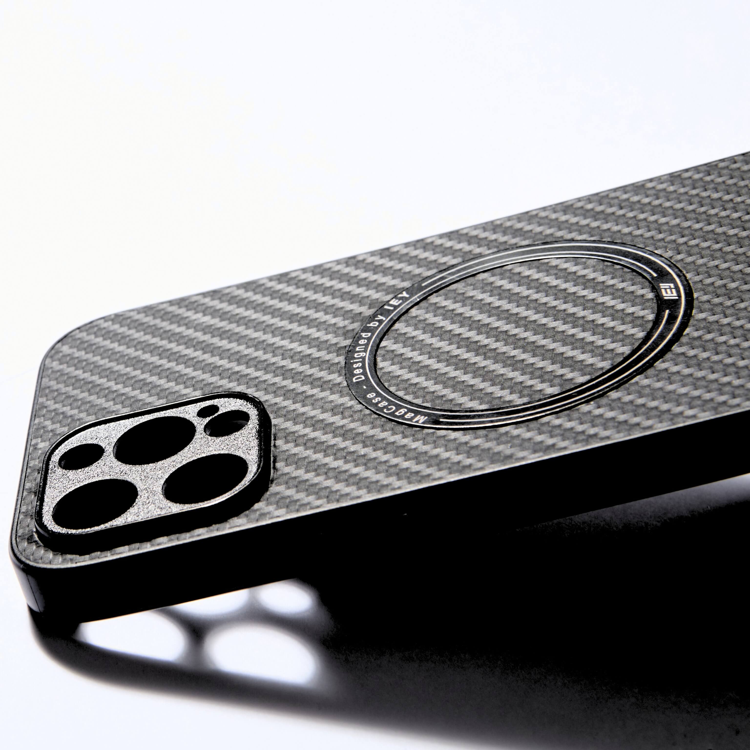 Funda MagSafe negra con textura tipo fibra de carbono, vista diagonal con aro imantado grabado y diseño ultraligero #color_negro