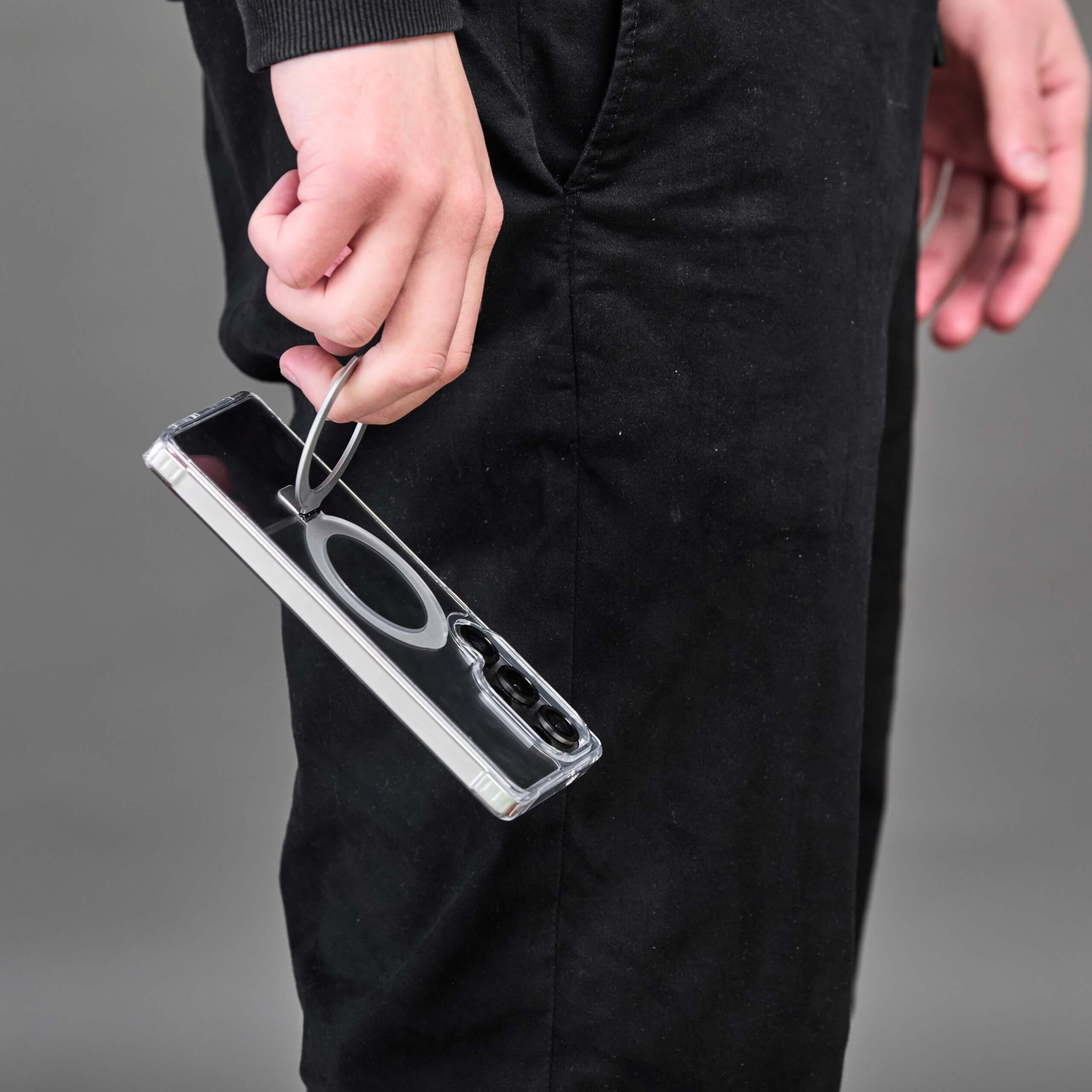 Persona sujetando el teléfono con funda transparente y aro magnético, de costado.