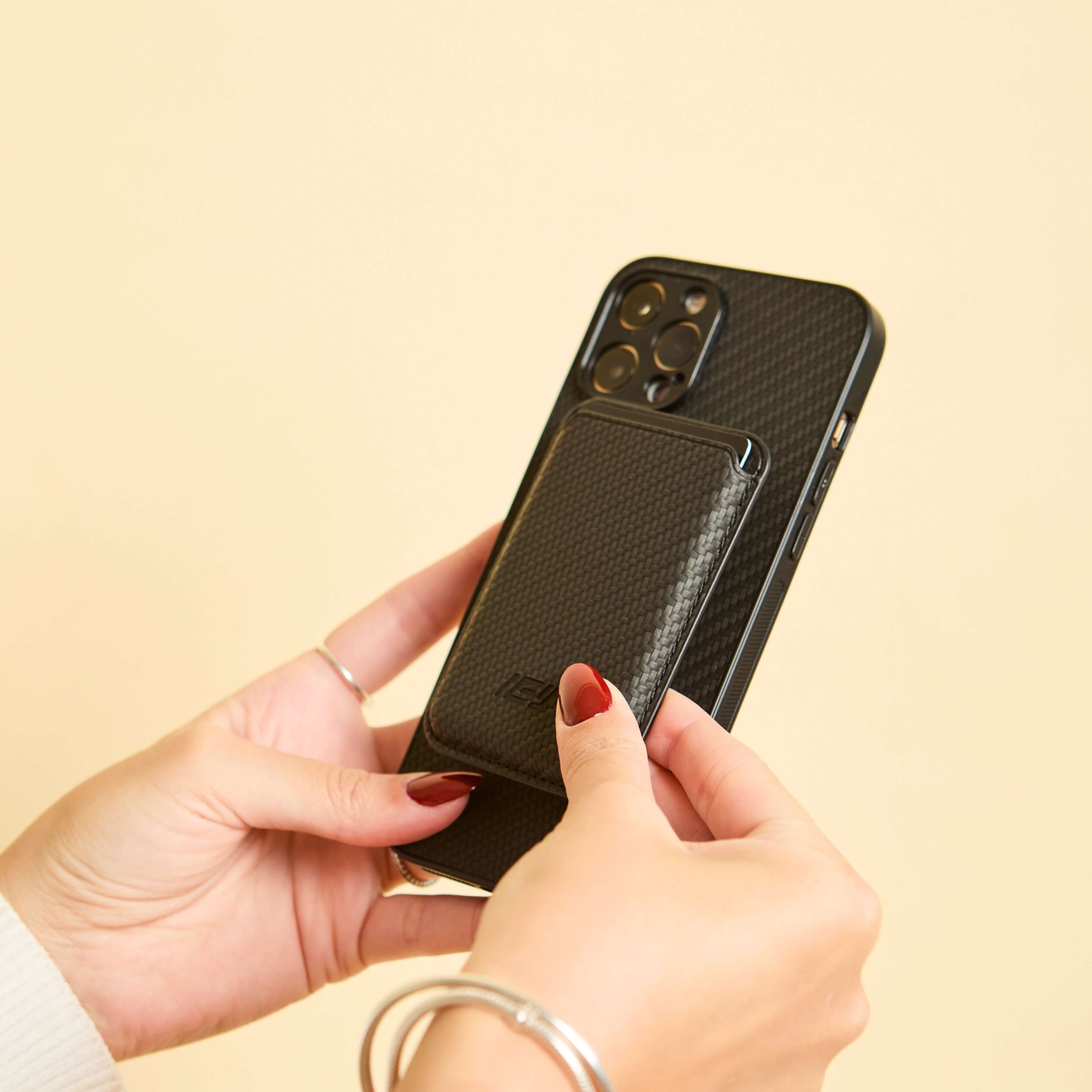 Manos mostrando el combo MagSafe negro en vertical, ideal para destacar su textura y estilo elegante. #color_negro