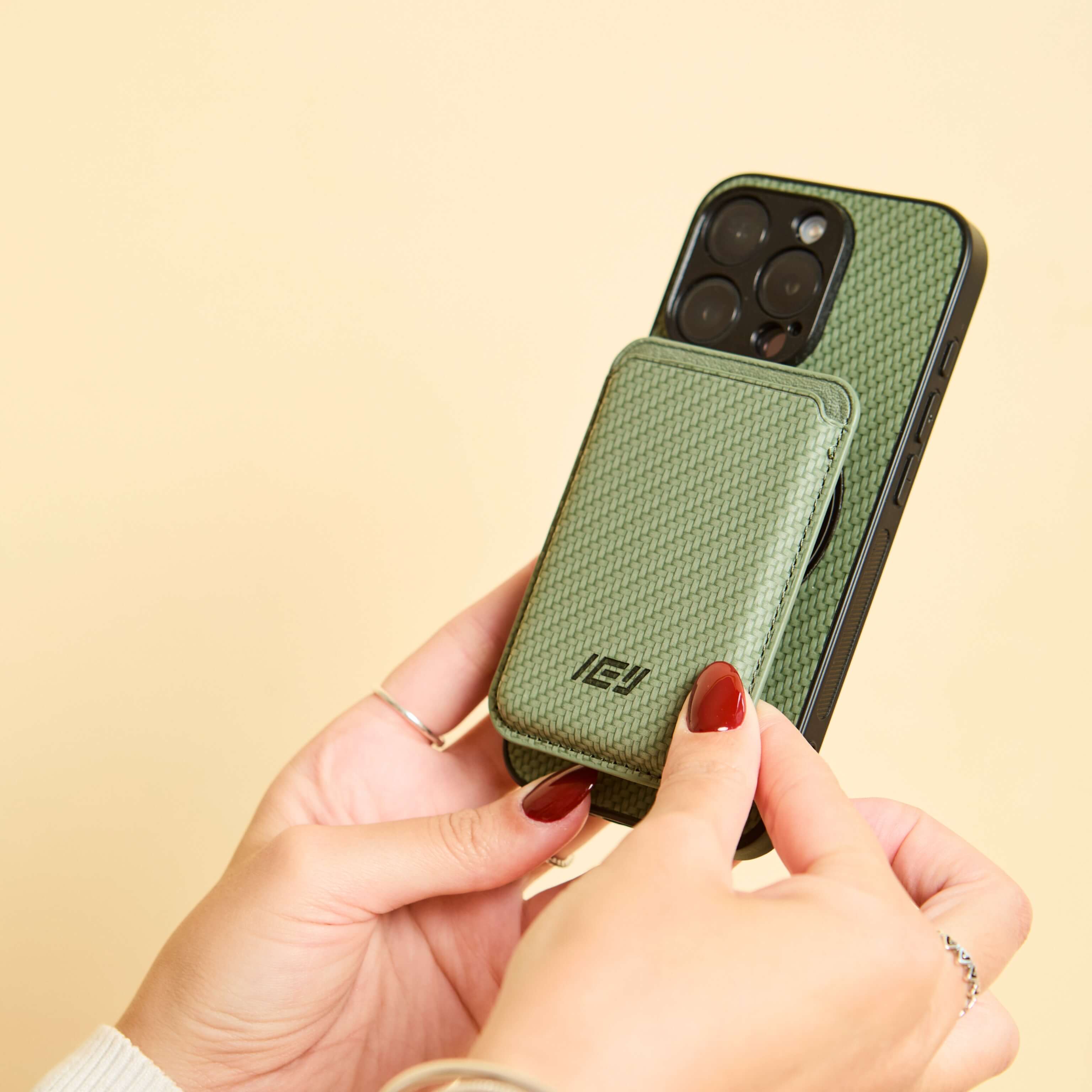Mujer sosteniendo iphone con Funda Magsafe carbon y Magwallet integrada de color verde #color_verde