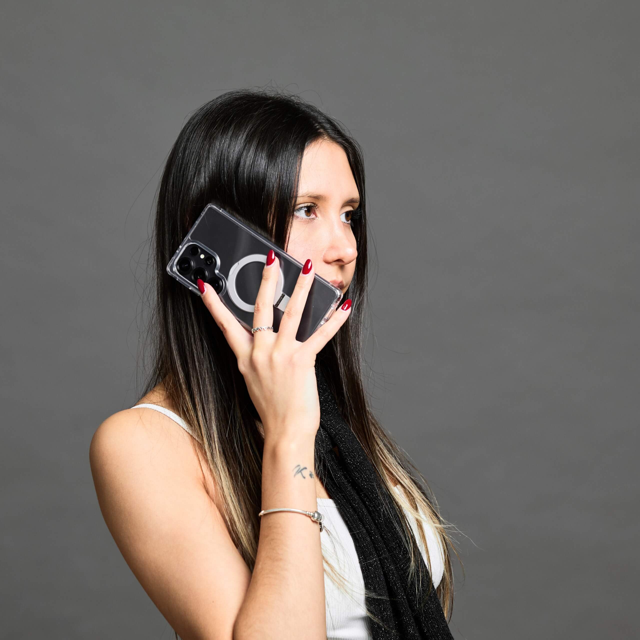 Mujer hablando por teléfono Samsung S25 Ultra con funda y aro magnético, fondo gris oscuro