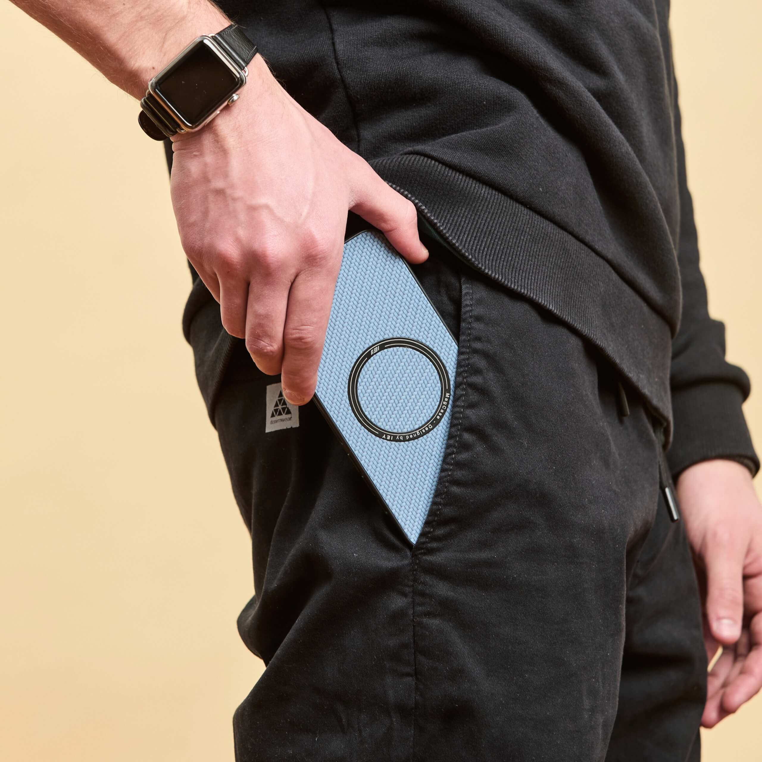 Hombre guardando un iPhone con funda MagSafe azul en el bolsillo.