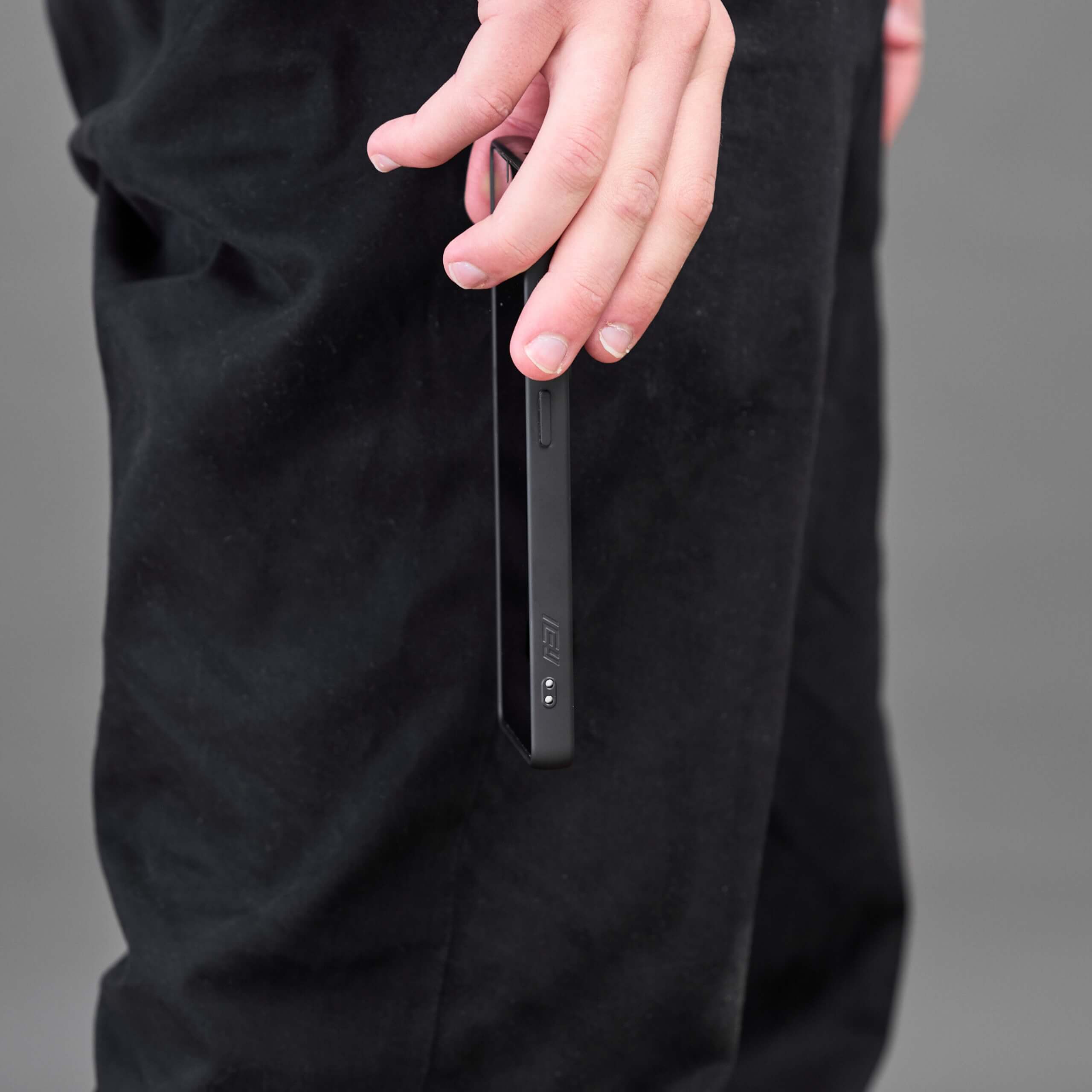 Persona sosteniendo un Samsung Galaxy con funda MagSafe negra en la mano, vista lateral.