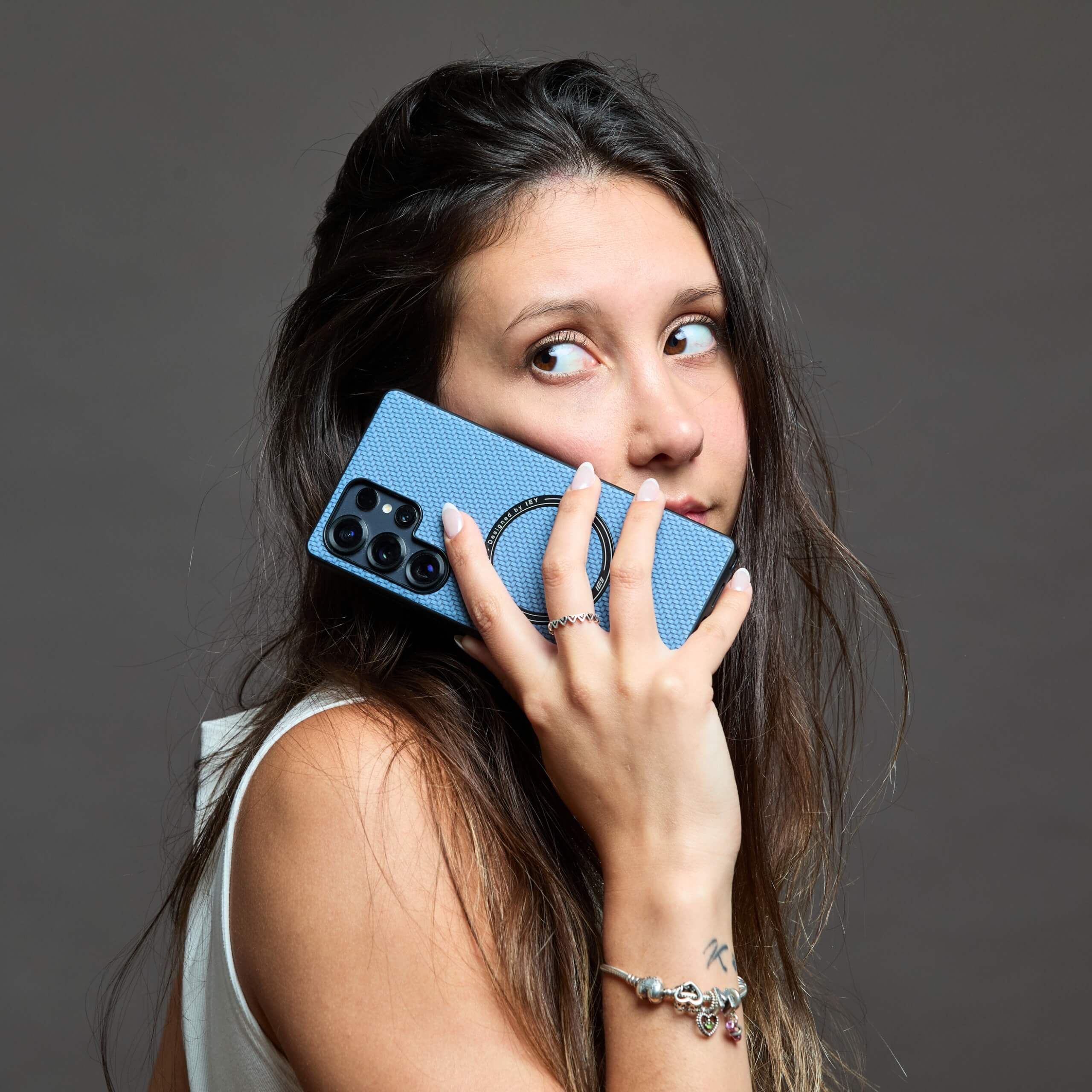 Funda MagSafe azul en Samsung, asomando desde el bolsillo trasero de un jean gris claro, con cinturón burdeos y suéter blanco #color_azul