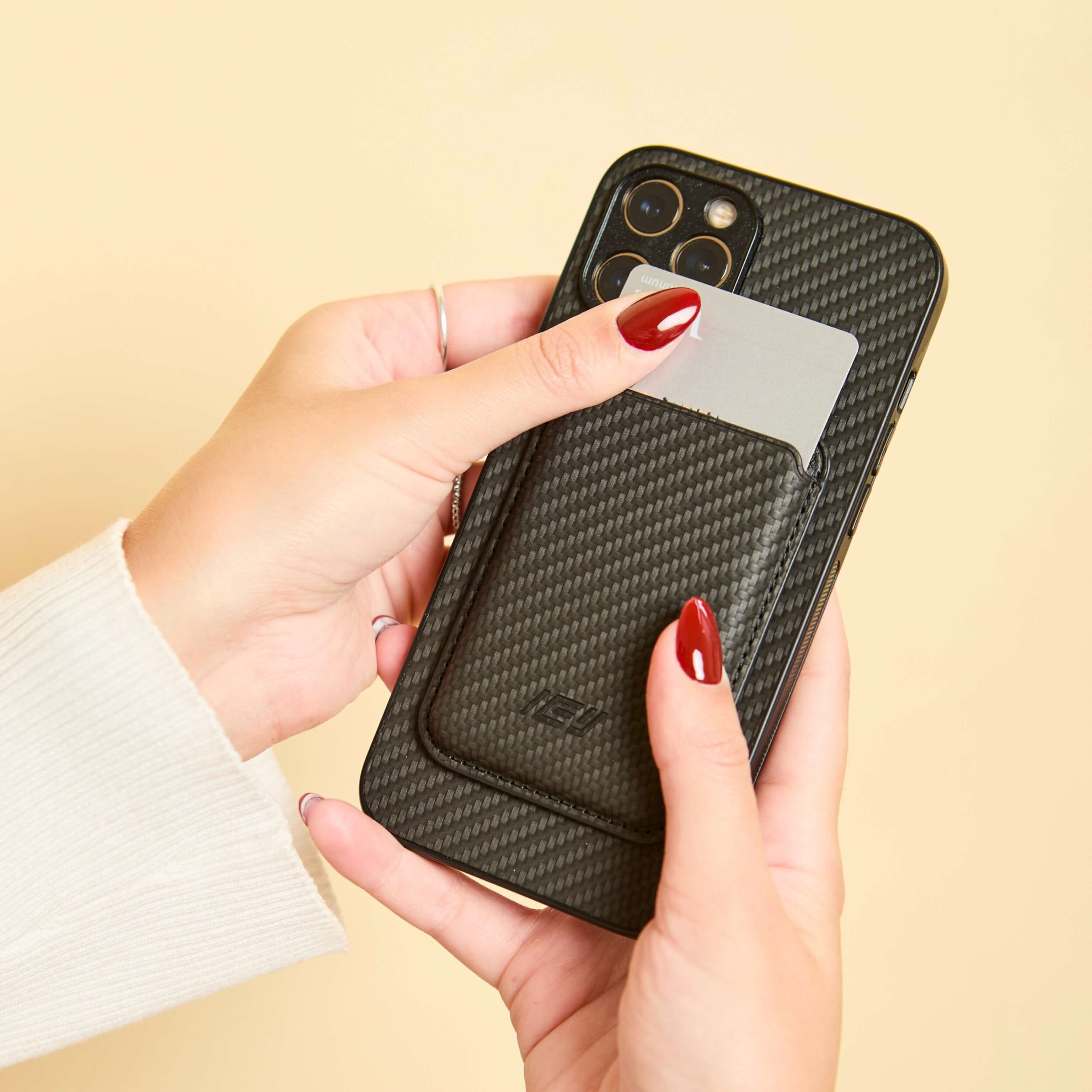 Mano insertando una tarjeta en la billetera MagSafe negra, demostrando funcionalidad diaria. #color_negro