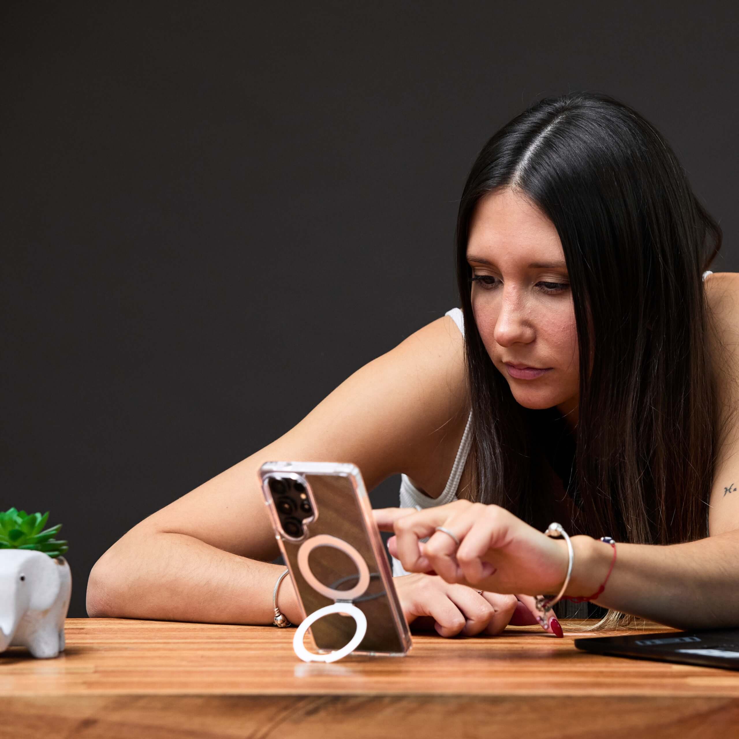 Mujer hablando por teléfono Samsung S25 Ultra con funda transparente con aro magnético, fondo gris oscuro.