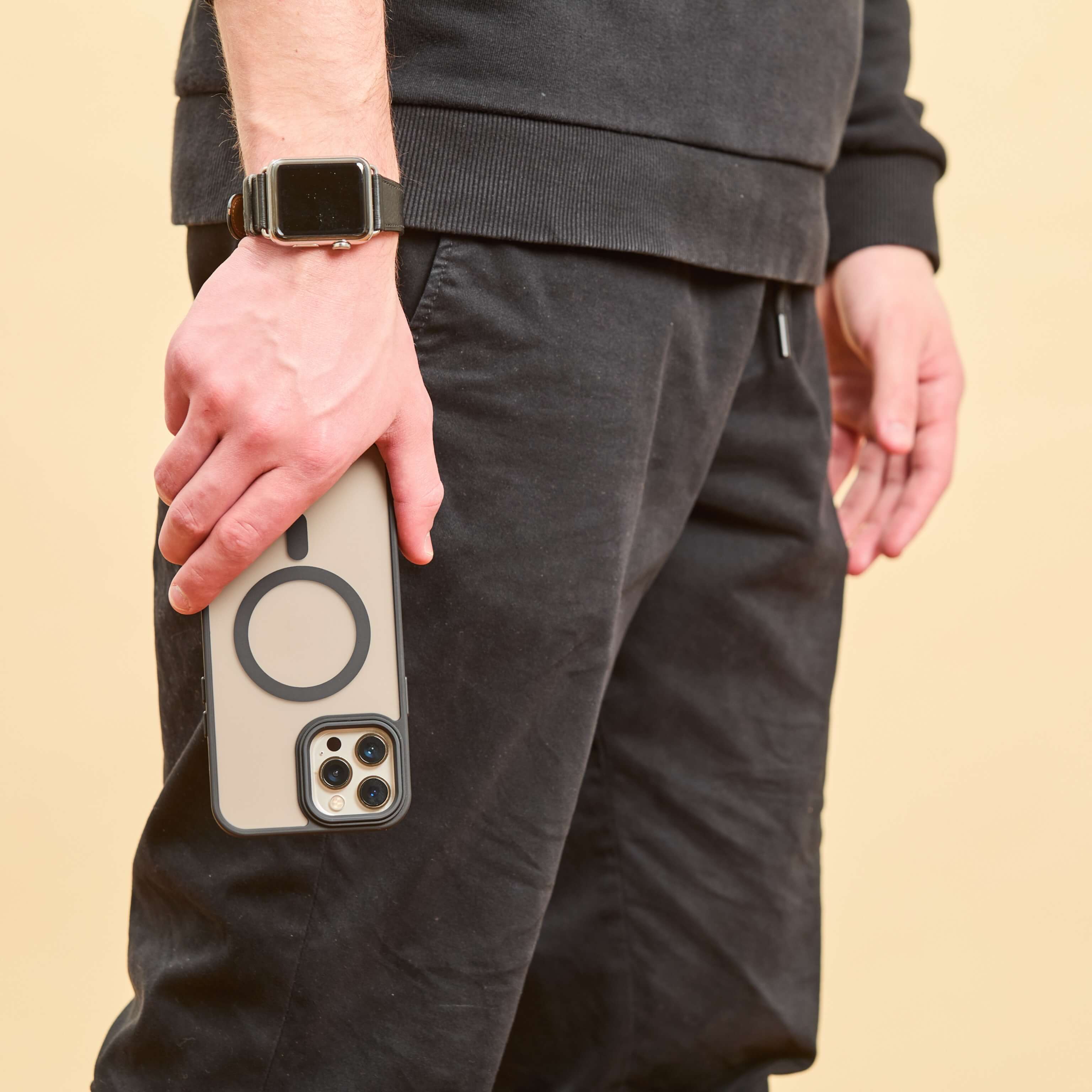 Hombre sosteniendo iPhone con funda MagSafe negra en posición relajada, con diseño minimalista y aro imantado visible