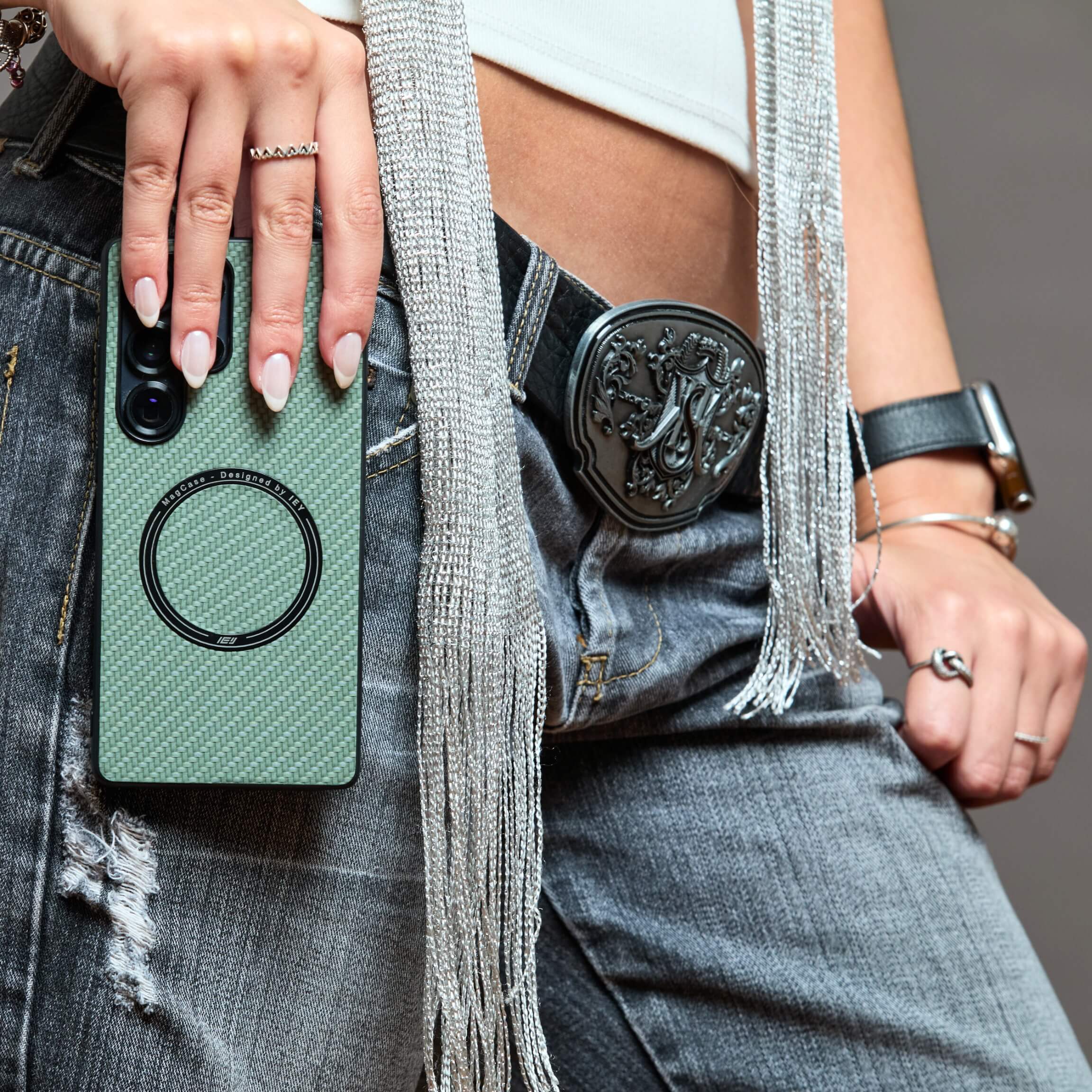 Funda MagSafe verde con textura de carbono para Samsung sostenida en el jean de una mujer #color_verde
