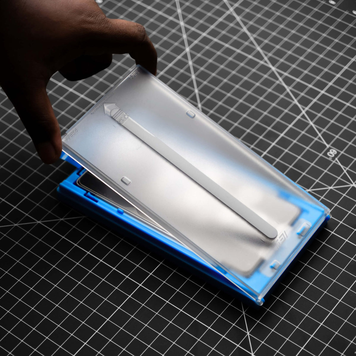 Aplicador guiado ApplyFit™ de IEY® durante la colocación del vidrio templado para iPhone, diseñado para facilitar una alineación precisa.
