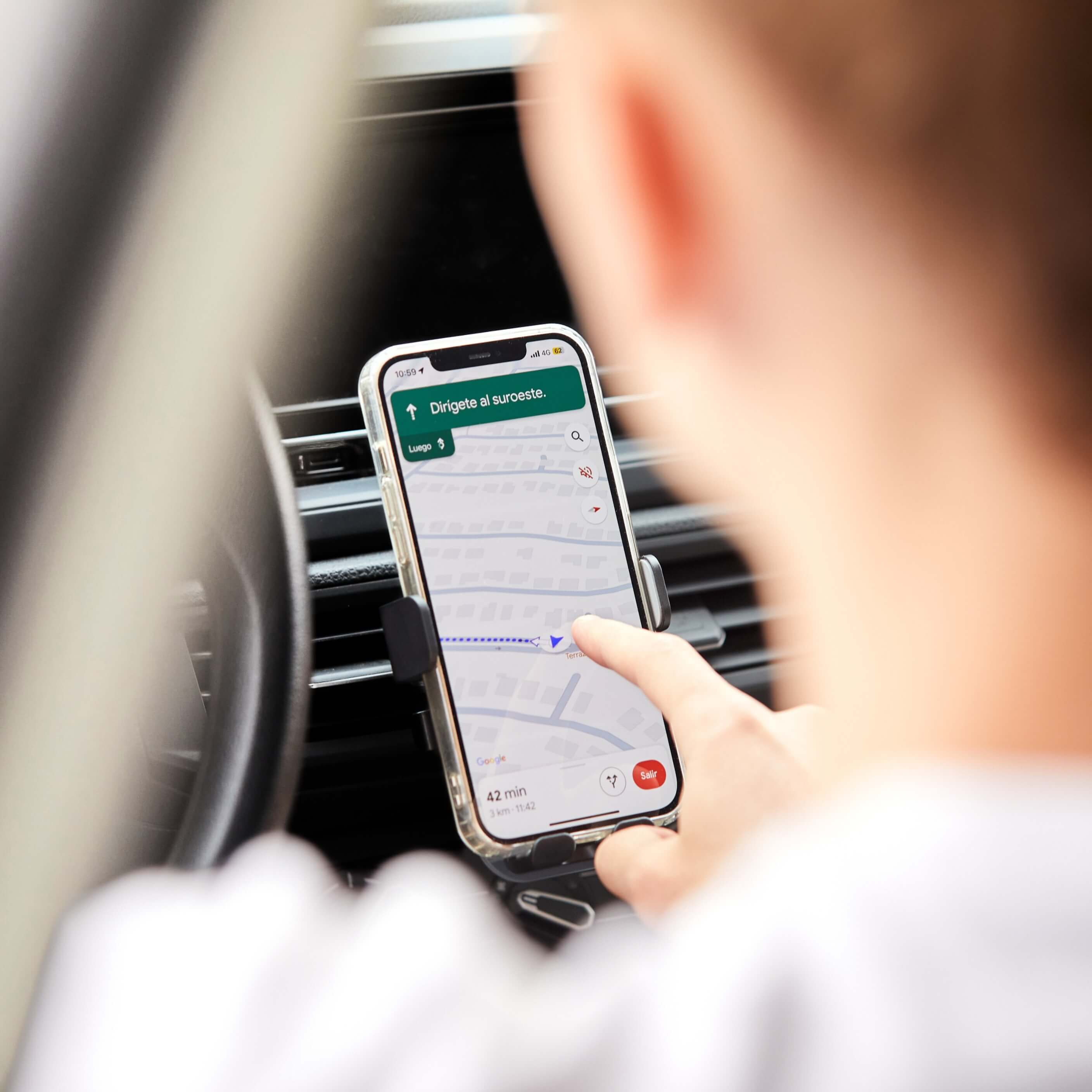 Persona usando GPS en celular sostenido por soporte de auto IEY montado en rejilla de ventilación