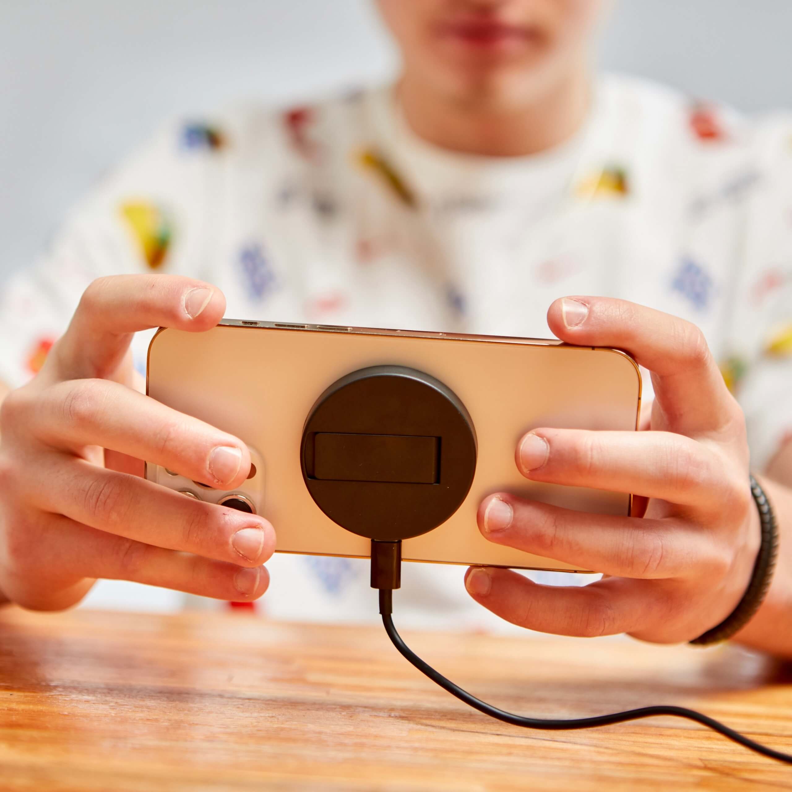 Persona sujetando un smartphone con cargador inalámbrico magnético conectado, ideal para jugar mientras se carga.