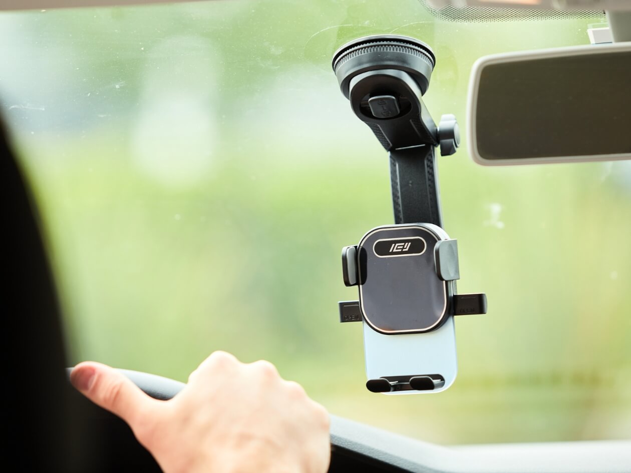Soporte de auto IEY con brazo extensible instalado en el parabrisas sujetando un smartphone durante la conducción