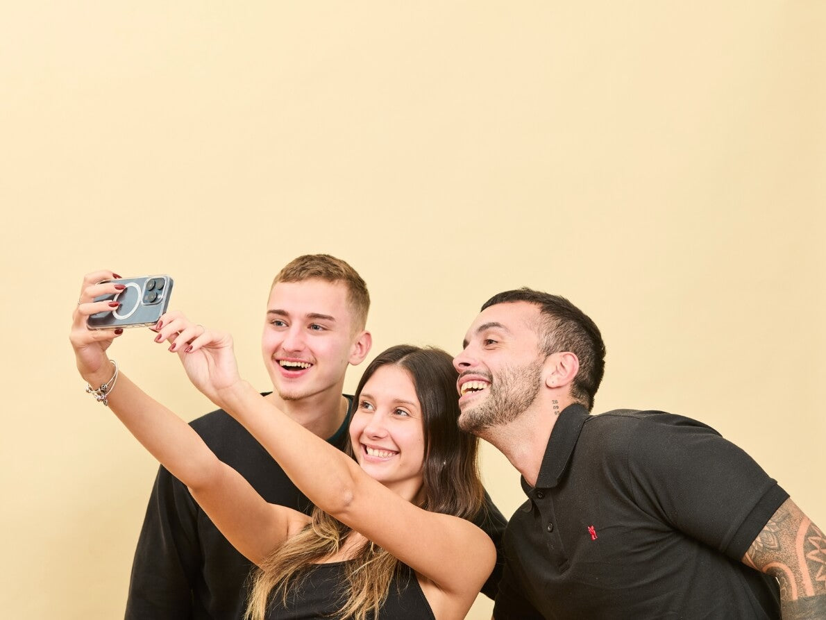 Tres personas sonriendo fotografiandose con su iPhone con Funda MagSafe Transparente
