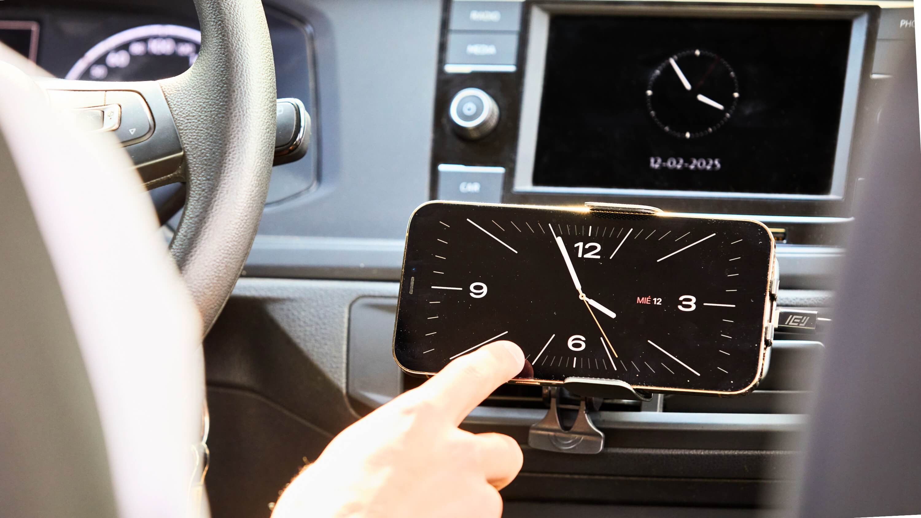 Soporte magnético IEY en auto con celular mostrando reloj digital, fijado en ventilación central