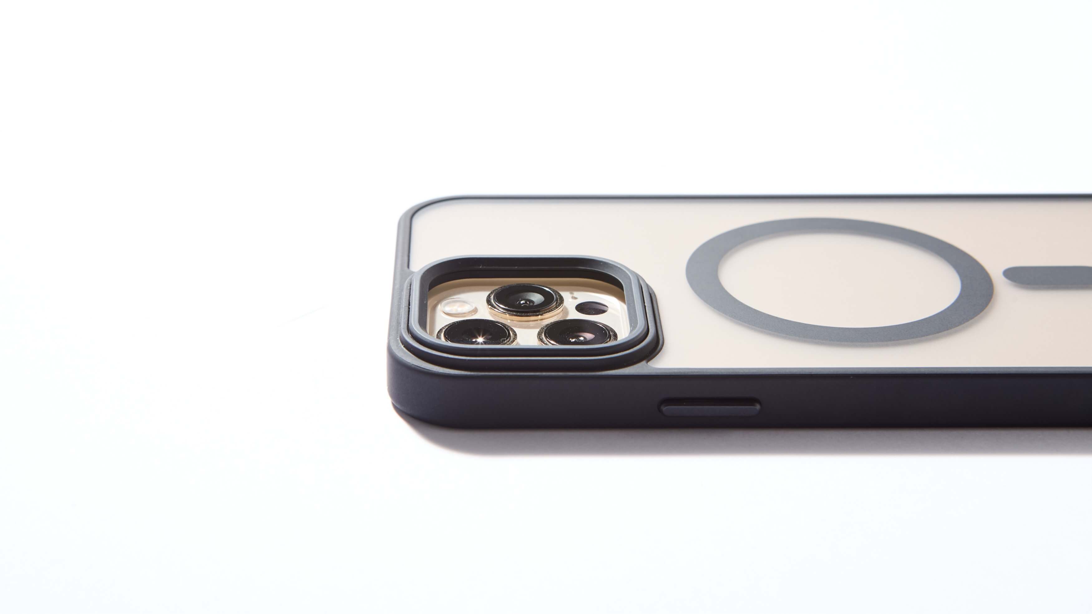 Funda MagSafe negra para iPhone apoyada de lado, con aro imantado visible y bordes elevados de protección para cámara