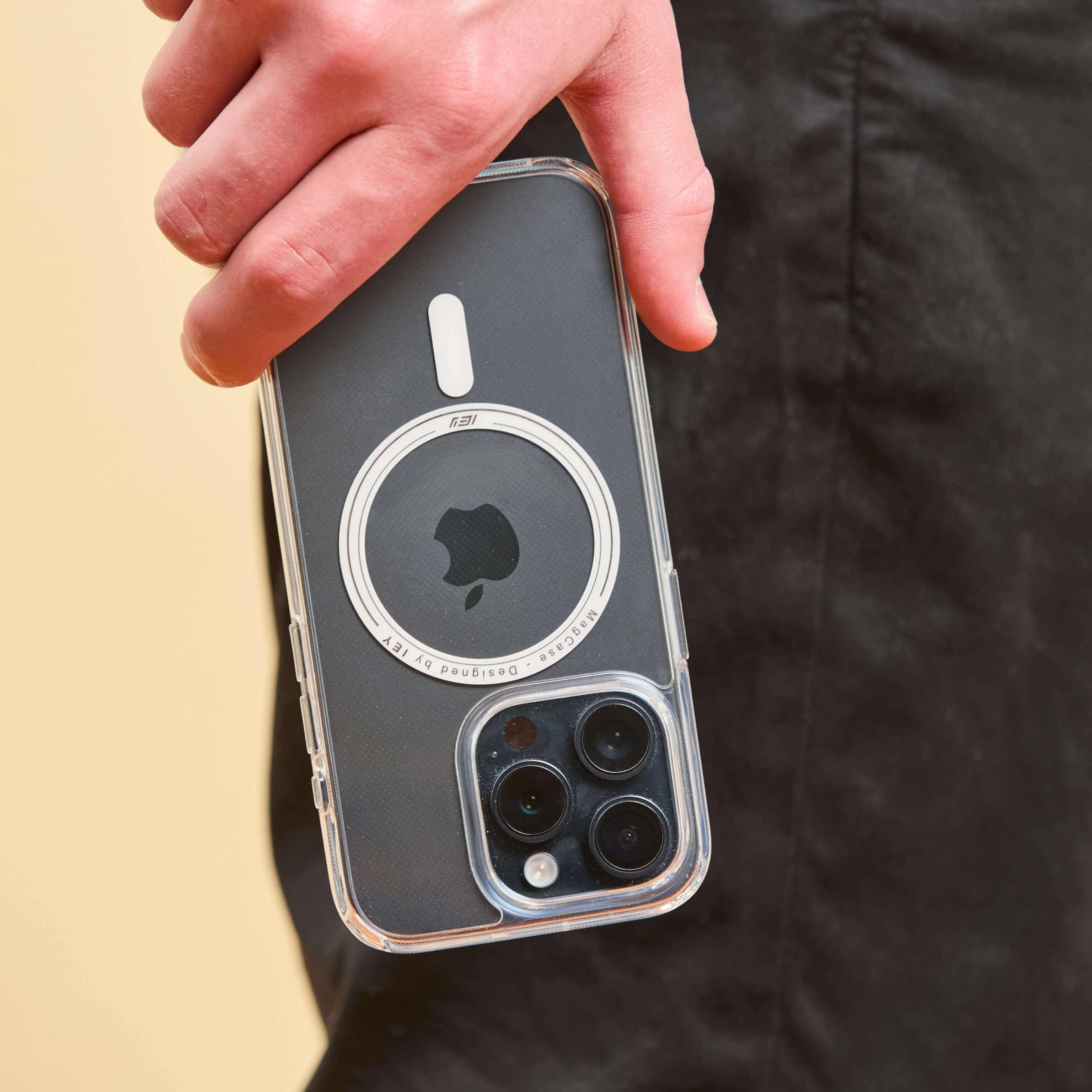 Funda MagSafe transparente para iPhone sostenida con la mano, con diseño minimalista y aro imantado en primer plano