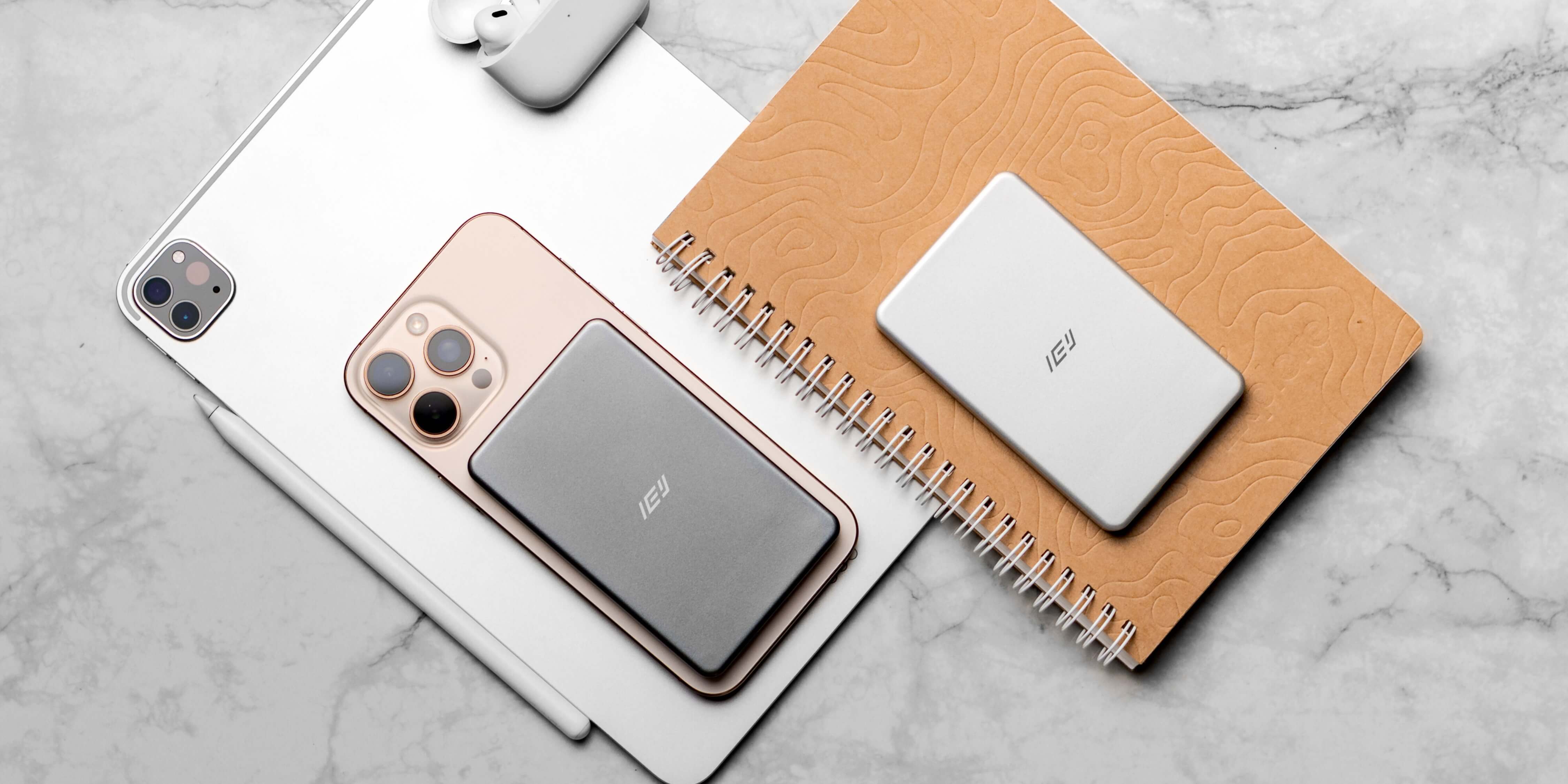 Escritorio minimalista con estación de carga inalámbrica IEY 3 en 1, mostrando un iPhone, auriculares y reloj sin cables visibles.