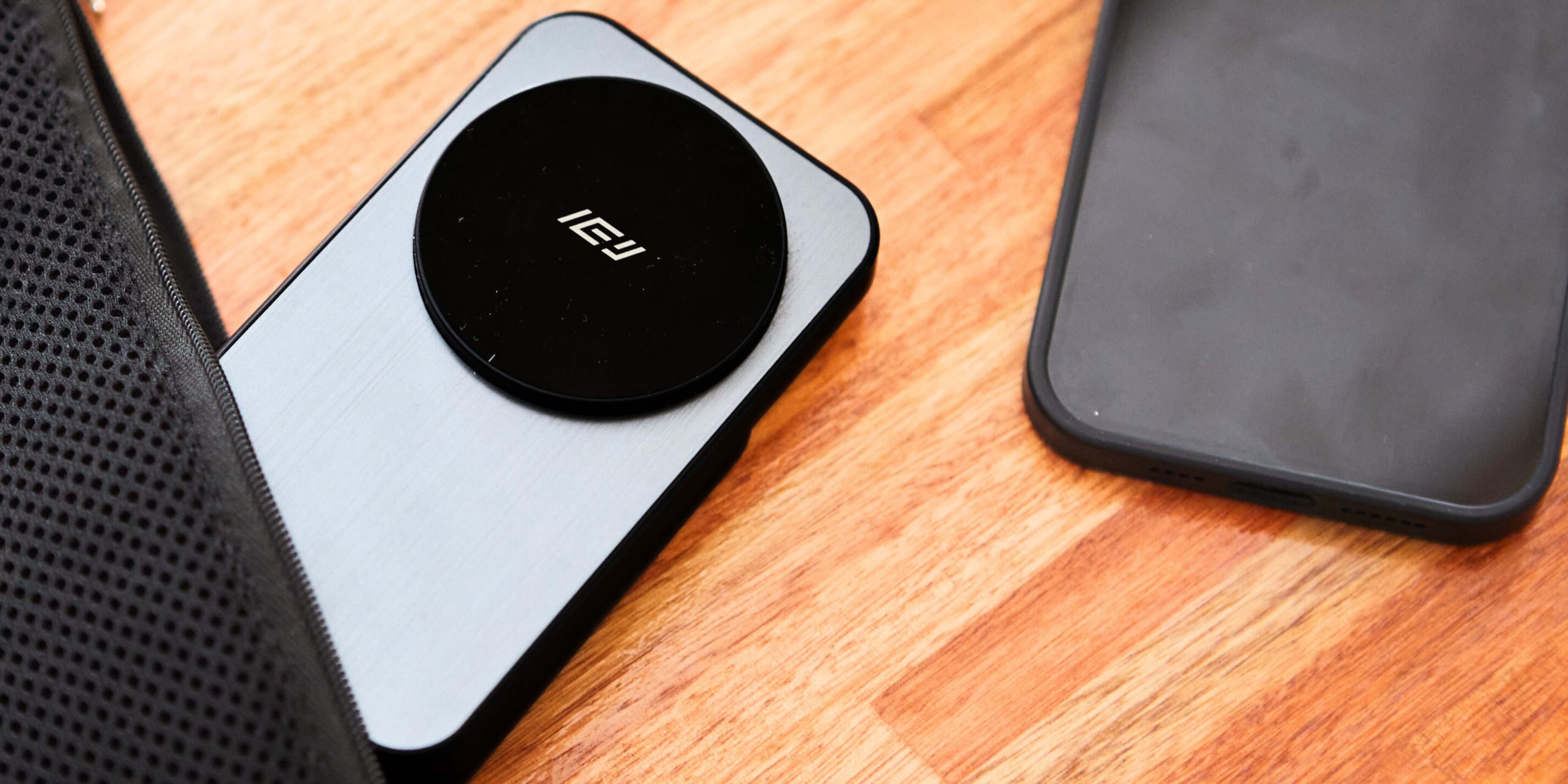 Cargador inalámbrico MagSafe de IEY en uso junto a un smartphone, sobre una mesa de madera