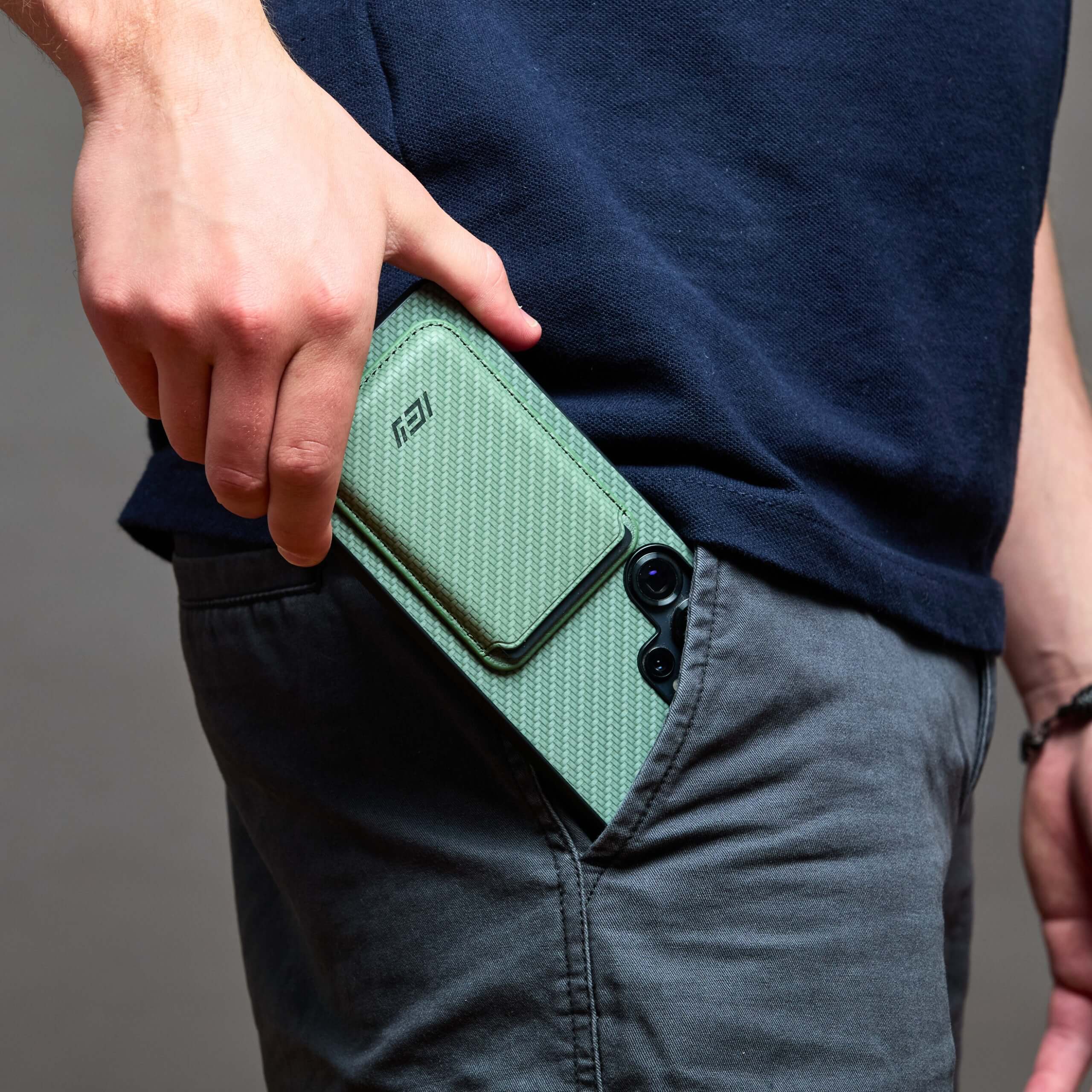 Funda MagSafe IEY® verde con wallet magnético guardada en bolsillo trasero #color_verde