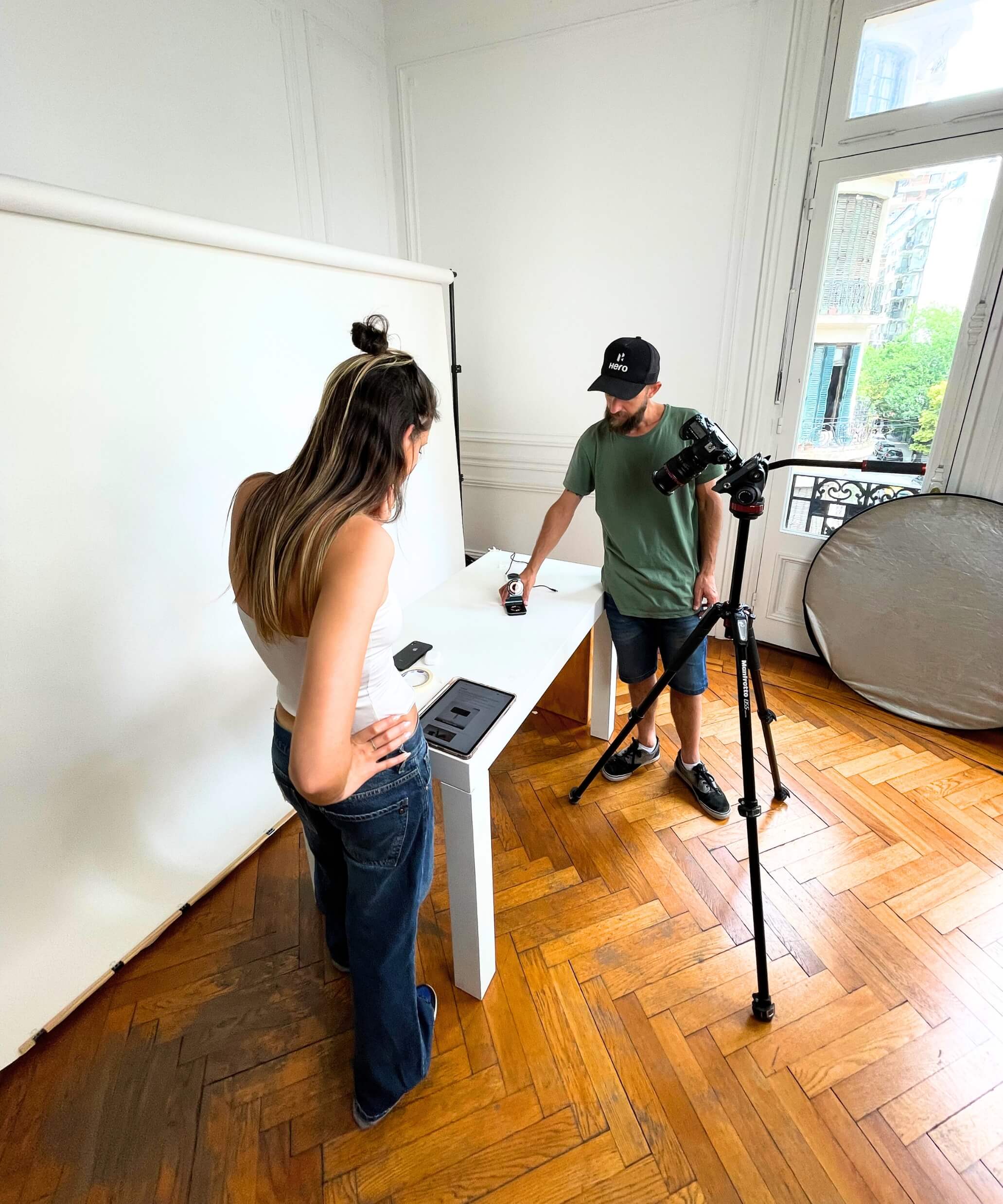 Sesión de fotos de producto IEY en estudio, con fotógrafo ajustando encuadre y asistente preparando la escena sobre fondo blanco