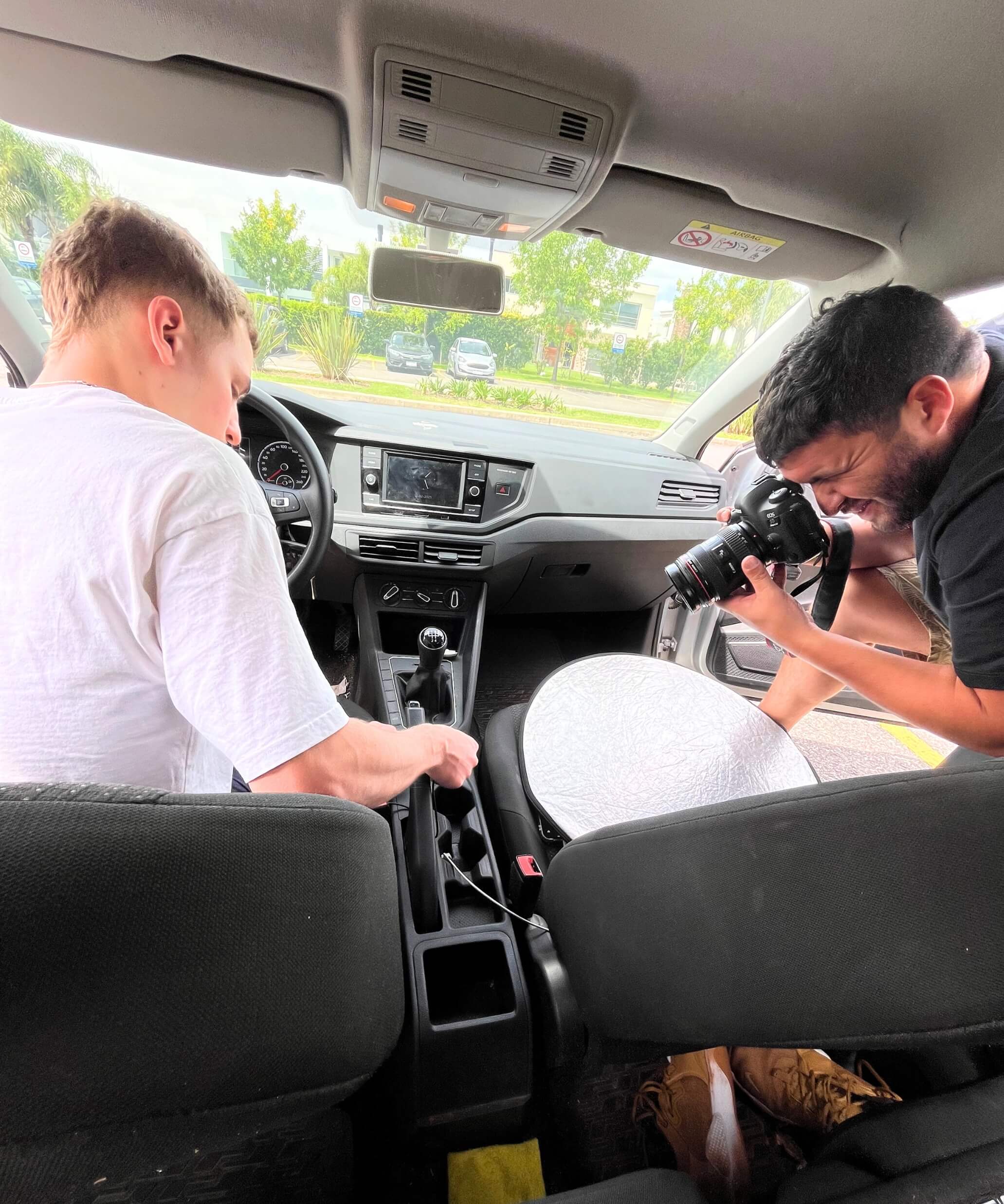 Producción de contenido en auto: fotógrafo capturando instalación de accesorio IEY mientras otra persona posiciona el producto en la consola central