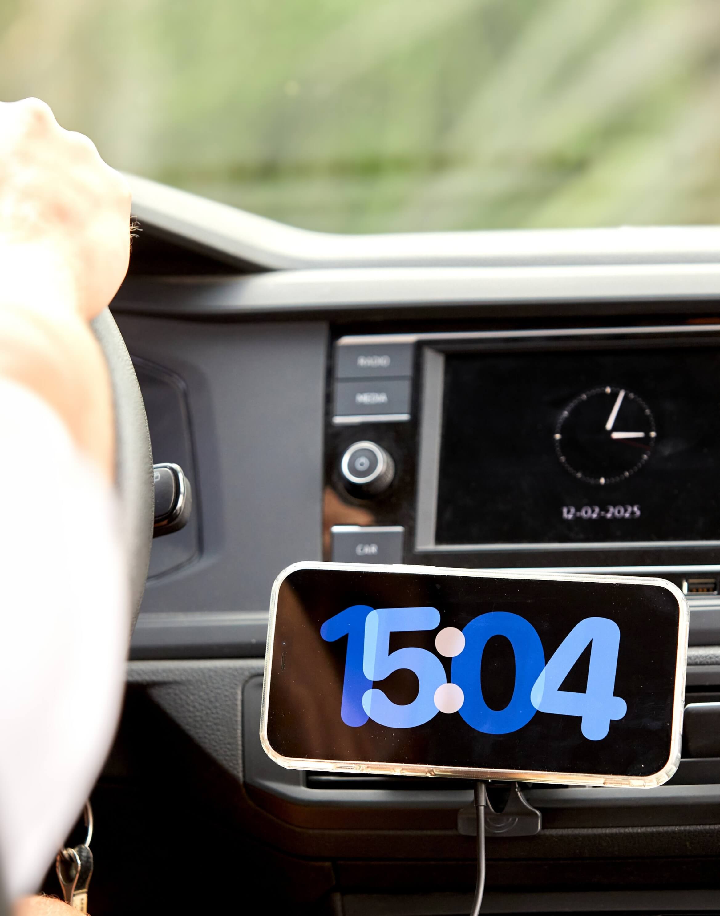 Soporte de auto IEY con teléfono en modo horizontal mostrando la hora y conectado con cable de carga