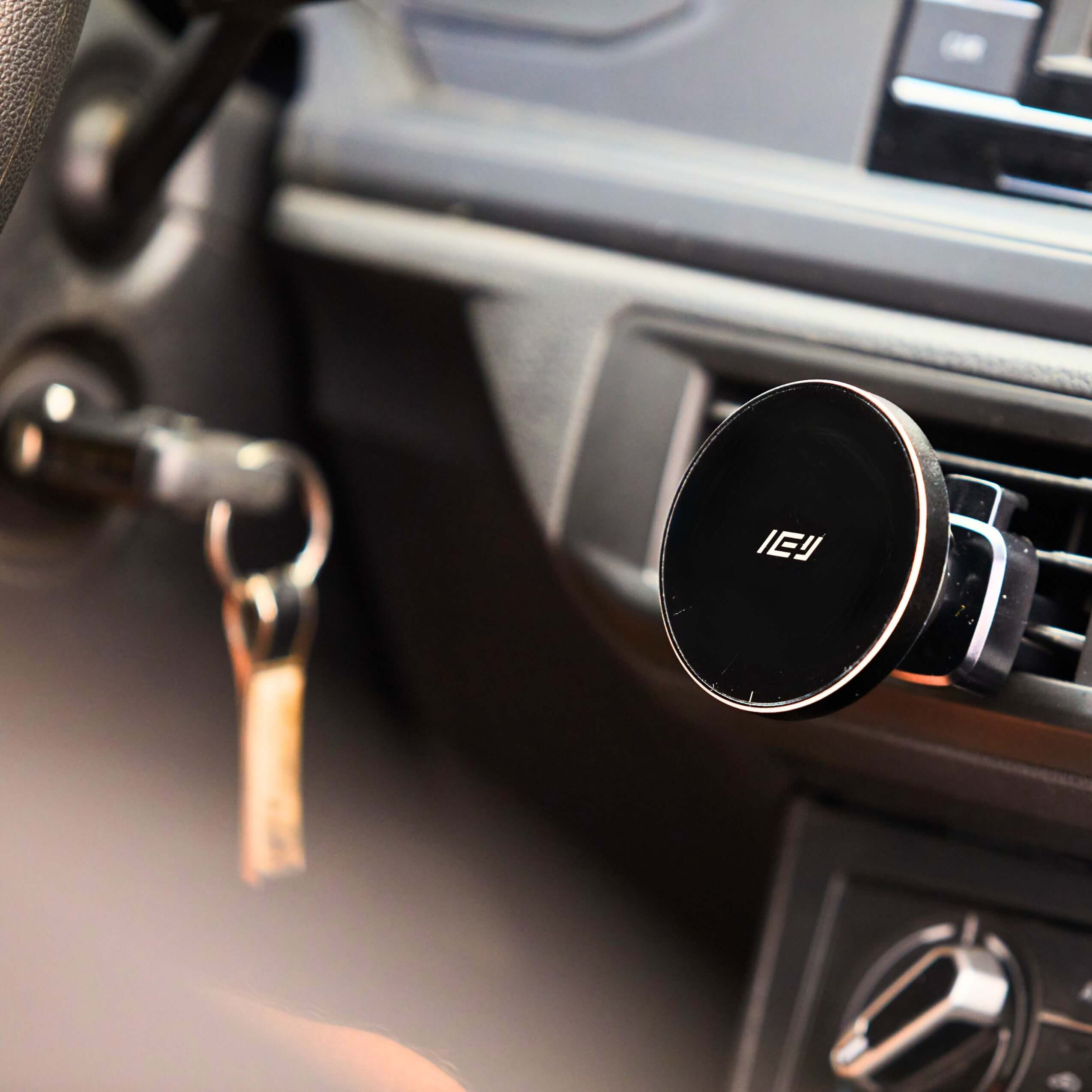 Cargador inalámbrico magnético IEY instalado en la rejilla del auto, con diseño elegante en negro brillante y fijación segura
