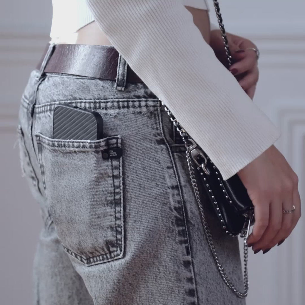 Billetera MagSafe Carbon negra guardada en el bolsillo trasero de un jean claro #color_negro
