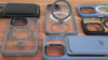 Fundas para iPhone con anillo soporte desplegado y variedad de colores, dispuestas sobre superficie de madera.